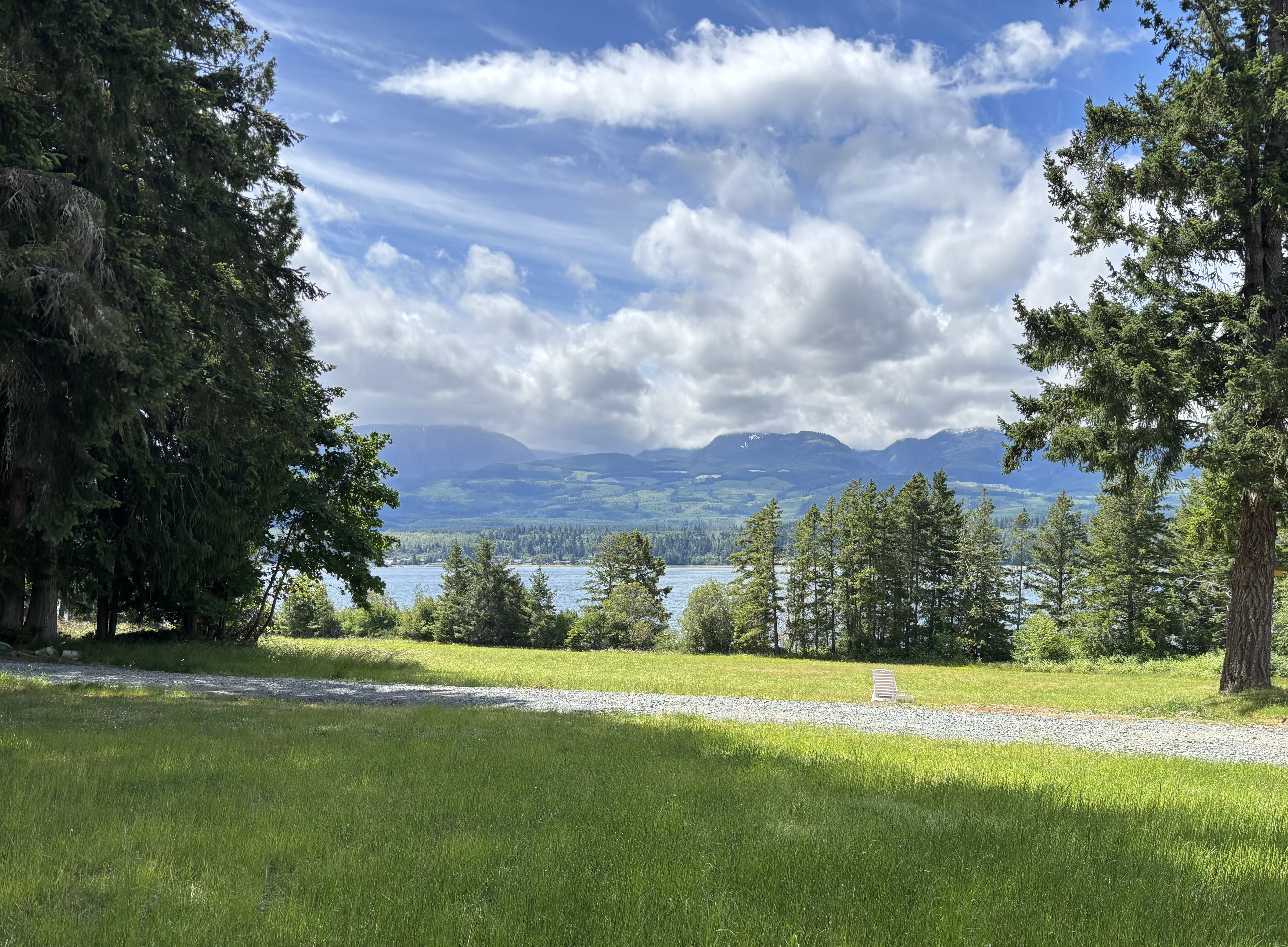 A chair on the lawn looking across Baynes Sound to the mountains